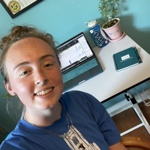 Lindsay, Virtual intern in New Zealand, posing in front of her work from home setup.